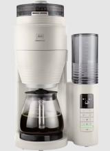 Image of white filter coffee machine with a glass jug filled with brewed coffee at the base, with a transparent water reservoir on the right, and a control panel and  display below it. 